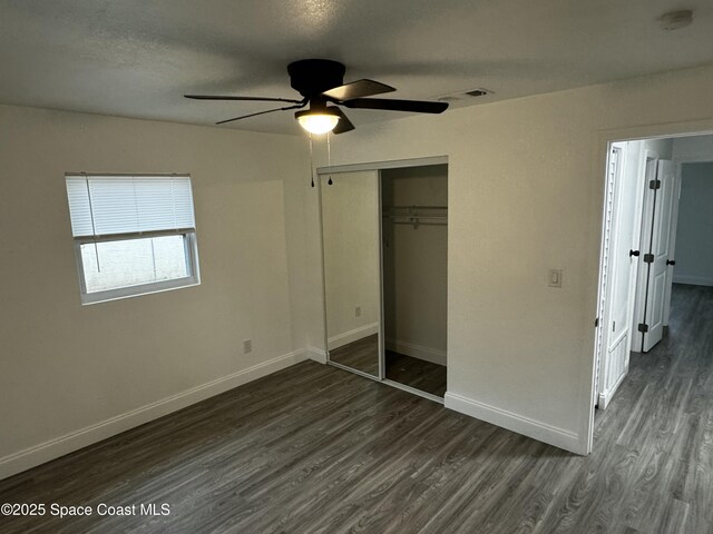 unfurnished bedroom featuring ceiling fan, a textured ceiling, dark hardwood / wood-style floors, and a closet