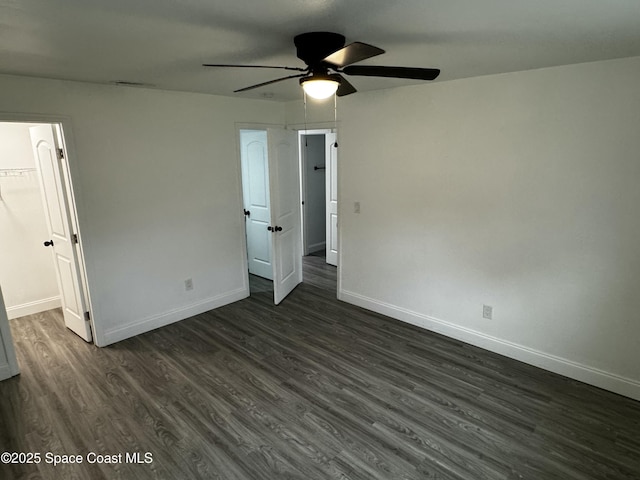 unfurnished bedroom with ceiling fan, dark hardwood / wood-style floors, a closet, and a walk in closet