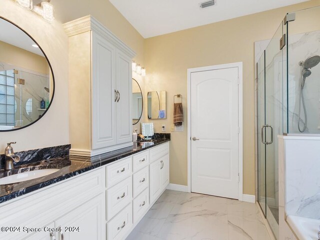 bathroom featuring a shower with door and vanity