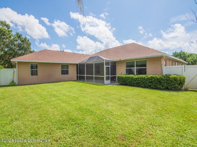 back of house featuring a lanai and a yard