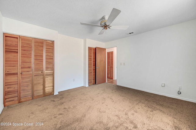 unfurnished bedroom with ceiling fan, carpet floors, and a closet