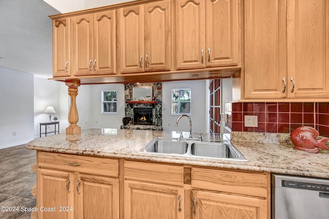 kitchen with dishwasher, a stone fireplace, decorative backsplash, and sink