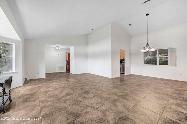 unfurnished living room featuring high vaulted ceiling and a chandelier