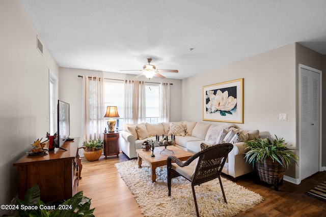 living room featuring ceiling fan, a textured ceiling, and hardwood / wood-style floors