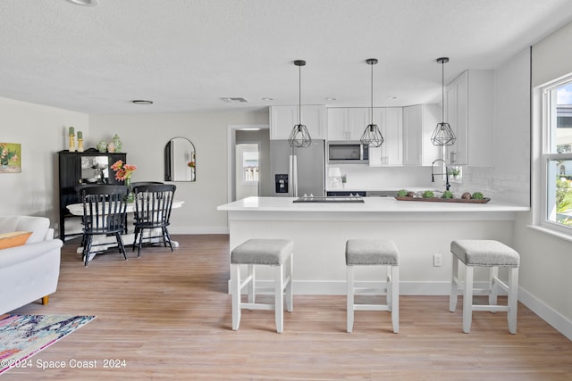 kitchen with stainless steel appliances, white cabinets, and plenty of natural light