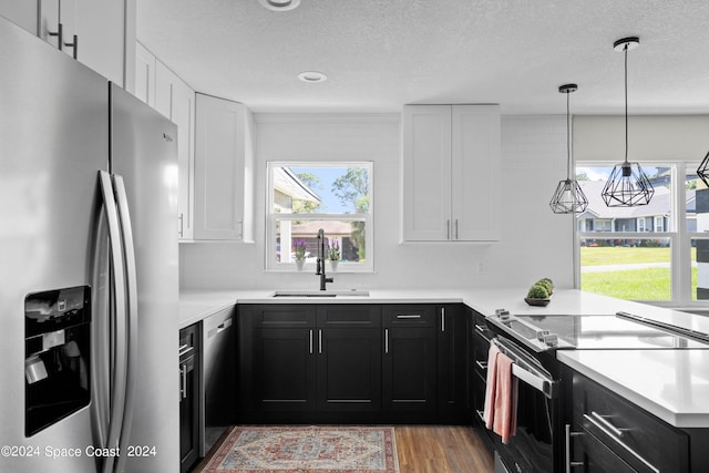 kitchen featuring stainless steel appliances, white cabinetry, hardwood / wood-style flooring, and sink