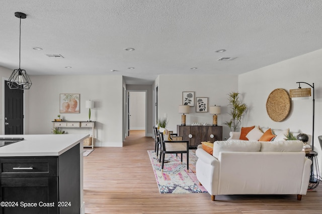 living room featuring light wood-type flooring and a textured ceiling