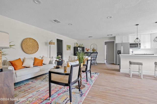 living room featuring light wood-type flooring and a textured ceiling