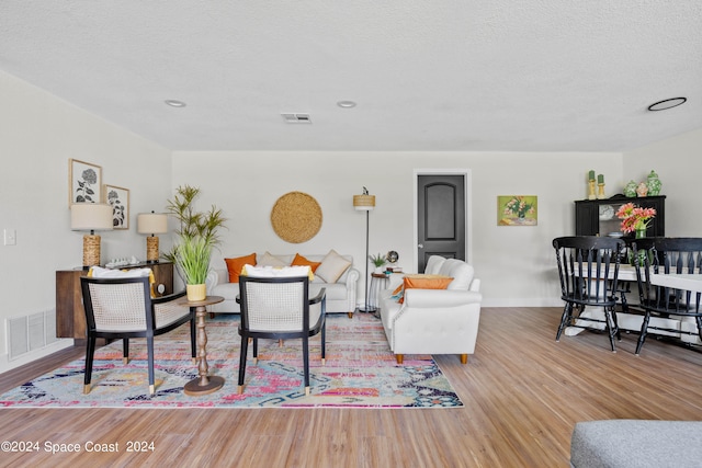 living room with a textured ceiling and light hardwood / wood-style floors