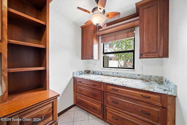 kitchen featuring ceiling fan, a textured ceiling, light stone countertops, and light tile patterned floors