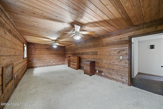 additional living space with light carpet, wood walls, and ceiling fan