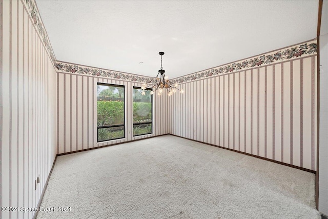 carpeted spare room with an inviting chandelier and a textured ceiling