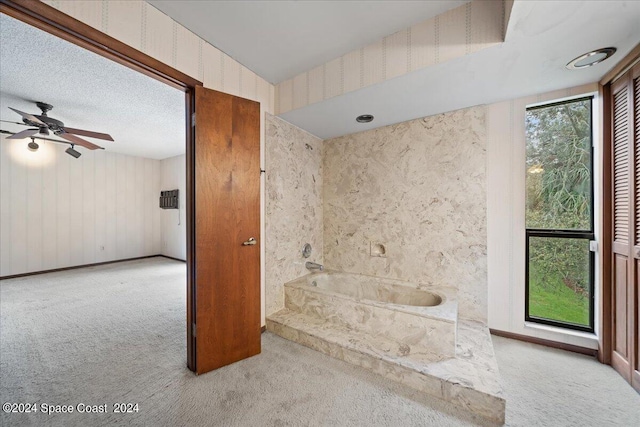 bathroom featuring ceiling fan, a bath, and a textured ceiling