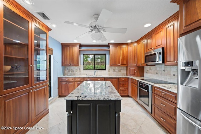 kitchen featuring a kitchen island, ceiling fan, decorative backsplash, stainless steel appliances, and sink