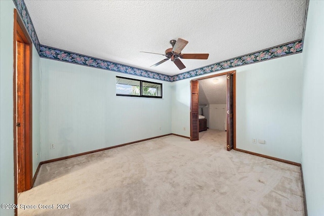 unfurnished bedroom featuring ceiling fan, a textured ceiling, and light carpet