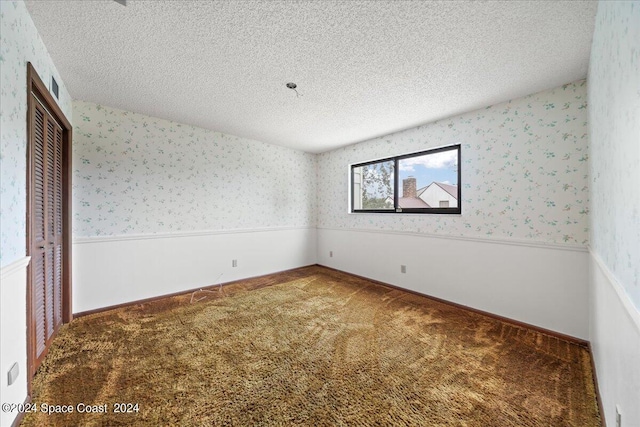 carpeted empty room featuring a textured ceiling