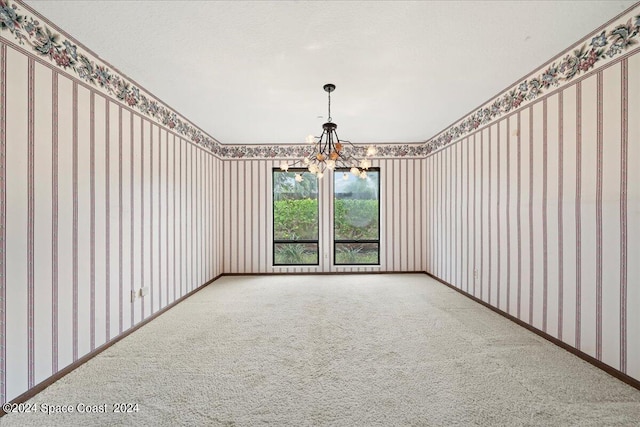 carpeted empty room with an inviting chandelier and a textured ceiling