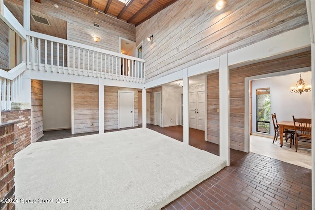 unfurnished bedroom featuring wooden walls, two closets, a towering ceiling, and wood ceiling