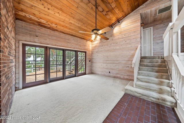 unfurnished living room with ceiling fan, dark colored carpet, wooden ceiling, vaulted ceiling, and wood walls