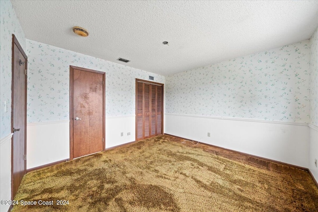 unfurnished bedroom with a textured ceiling, two closets, and carpet