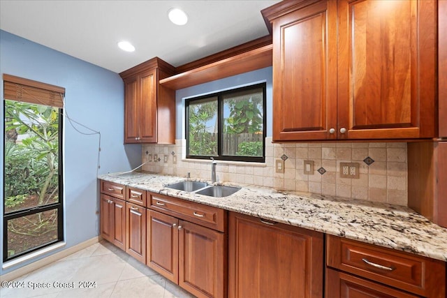 kitchen featuring plenty of natural light, backsplash, light stone countertops, and sink