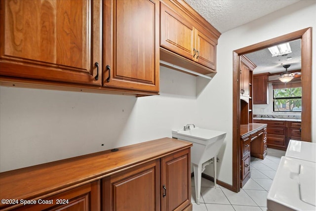 laundry room with cabinets, ceiling fan, washer and dryer, light tile patterned floors, and a textured ceiling