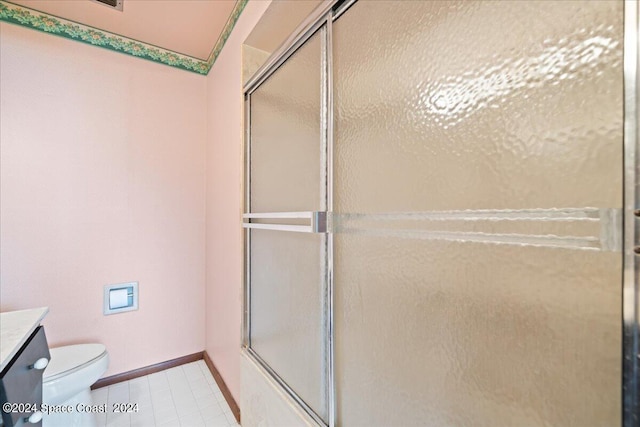 bathroom featuring vanity, toilet, tile patterned flooring, vaulted ceiling, and a shower with door