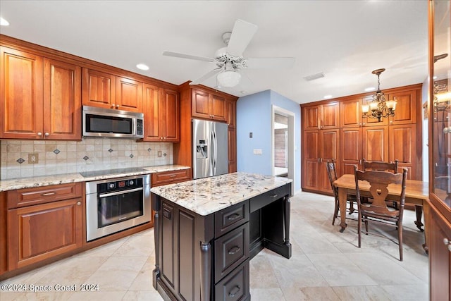 kitchen with light stone countertops, hanging light fixtures, tasteful backsplash, stainless steel appliances, and ceiling fan with notable chandelier