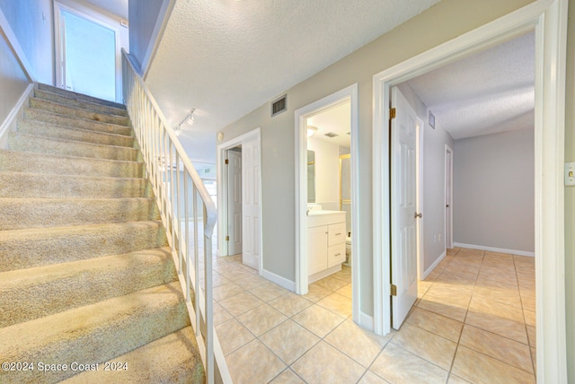 staircase with a textured ceiling and tile patterned floors