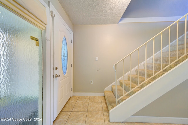 entryway with a textured ceiling and tile patterned floors