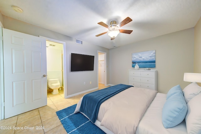 tiled bedroom featuring connected bathroom, ceiling fan, a walk in closet, and a closet