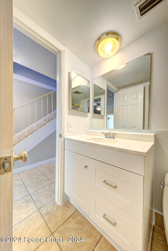 bathroom featuring tile patterned flooring, vanity, and toilet