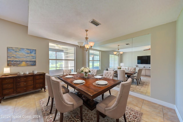 tiled dining area with a notable chandelier and a textured ceiling