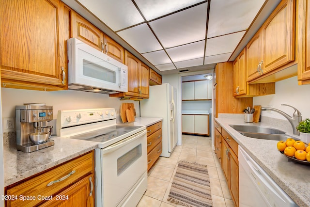 kitchen featuring white appliances, light stone counters, light tile patterned floors, and sink