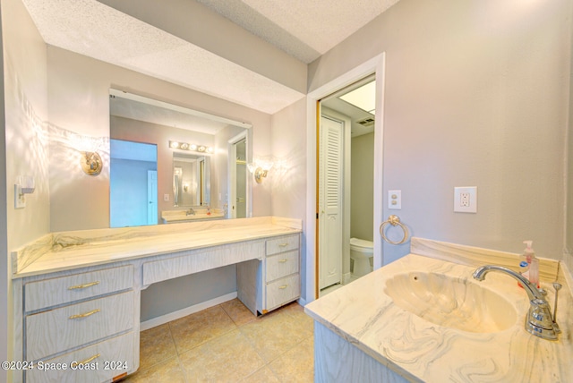 bathroom featuring vanity, toilet, a textured ceiling, and tile patterned floors