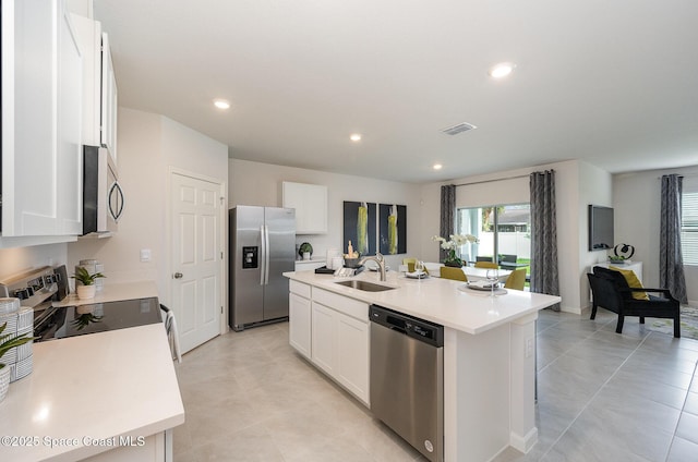 kitchen with stainless steel appliances, a kitchen island with sink, sink, and white cabinets