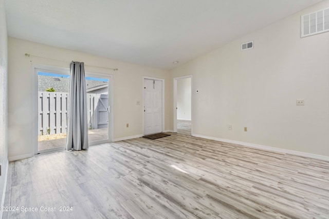 spare room featuring lofted ceiling and light hardwood / wood-style floors