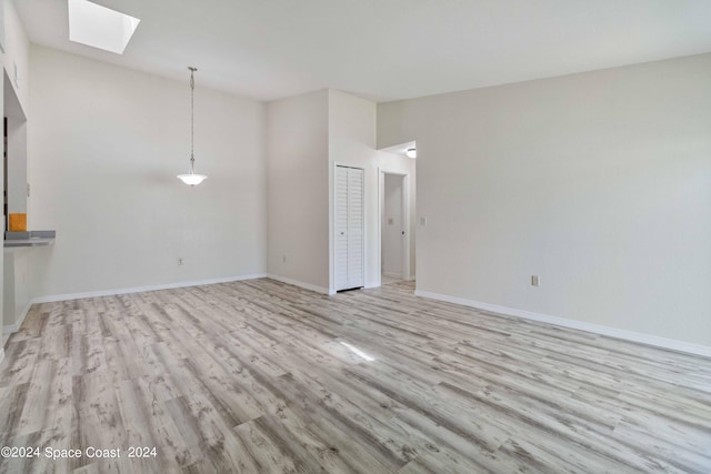 empty room featuring a skylight and light hardwood / wood-style floors