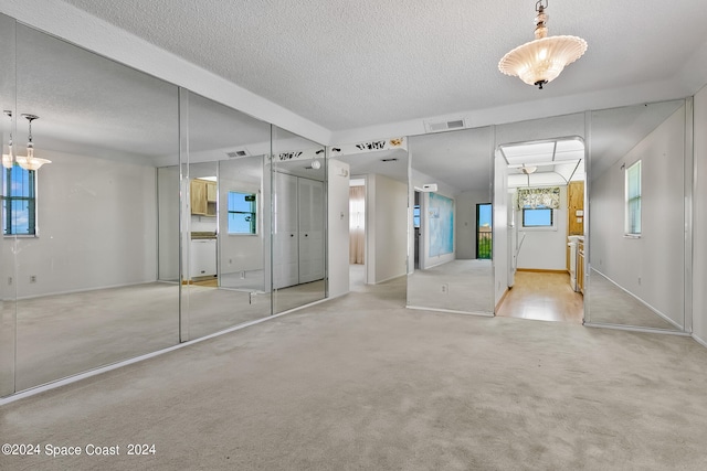 unfurnished bedroom featuring a textured ceiling and light carpet