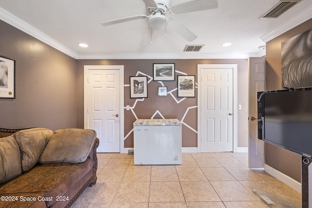 tiled living room featuring ceiling fan, a textured ceiling, and ornamental molding