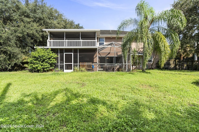 rear view of house featuring a sunroom, a lawn, and glass enclosure