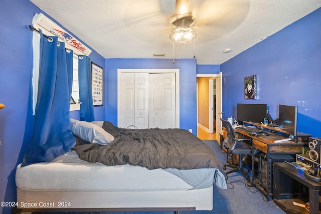 bedroom with a textured ceiling, carpet flooring, ceiling fan, and a closet