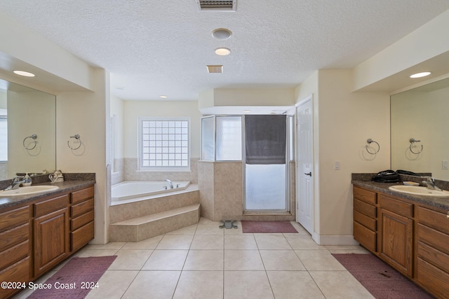 bathroom featuring plus walk in shower, tile patterned flooring, a textured ceiling, and vanity