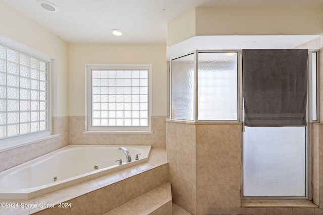 bathroom featuring a textured ceiling, plus walk in shower, and plenty of natural light