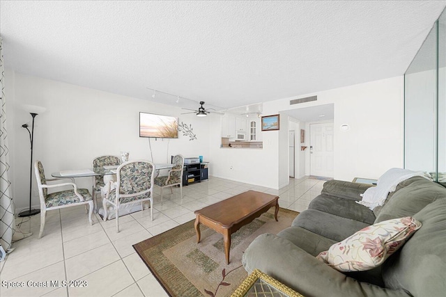 living room featuring ceiling fan, light tile patterned flooring, and a textured ceiling