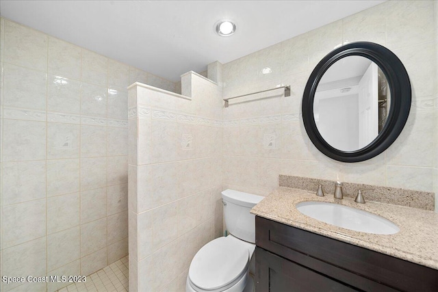 bathroom featuring vanity, a shower, tile walls, and toilet