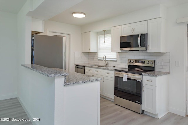 kitchen featuring appliances with stainless steel finishes, light hardwood / wood-style floors, white cabinetry, kitchen peninsula, and sink