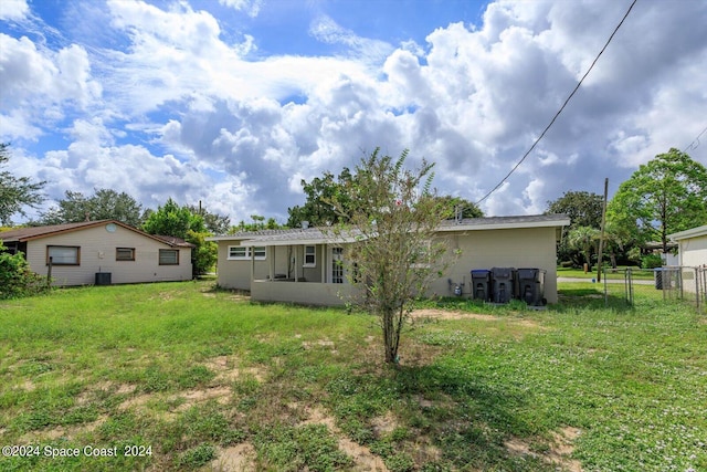 rear view of property with cooling unit and a yard