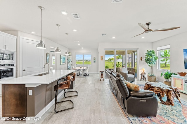 living room with light hardwood / wood-style flooring, ceiling fan, and sink