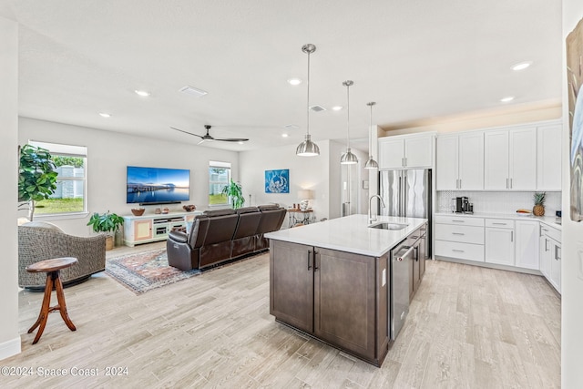 kitchen featuring pendant lighting, light hardwood / wood-style floors, an island with sink, white cabinets, and appliances with stainless steel finishes